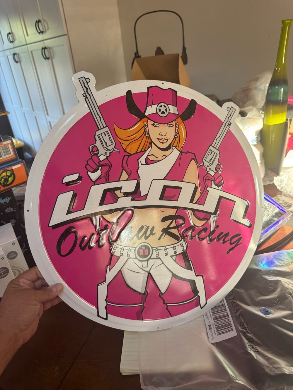 Icon Outlaw Racing metal sign features a vibrant pink background with a cowgirl
